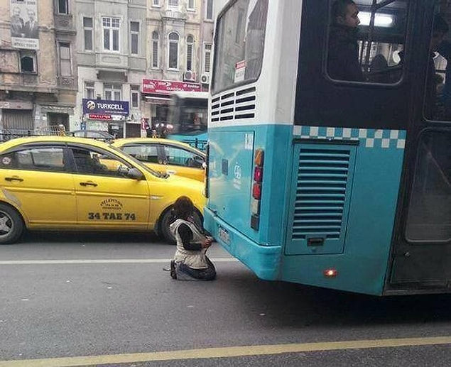 15. Otobüs egzozunun verdiği sıcaklıkla ısınmaya çalışan bir çocuk.