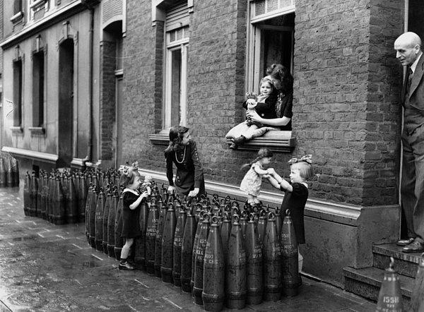 10. Evlerinin önündeki sıralanmış dolu kovanların arasında hiçbir şey yokmuş gibi bebekleriyle oynayan küçük kızlar, Münih, 1943.