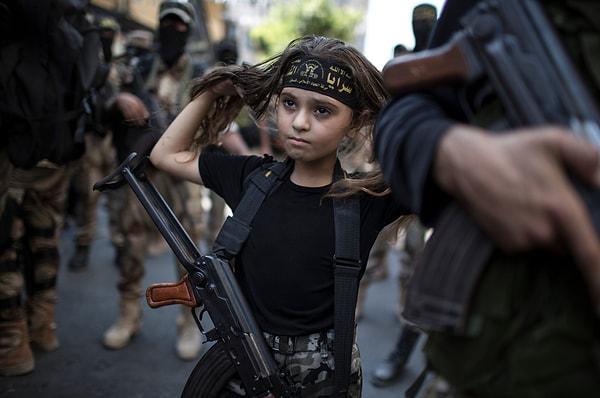 4. Gazze'de silahlı militanların arasında Kalaşnikov tüfeği taşıyan Filistinli bir kız çocuğu.