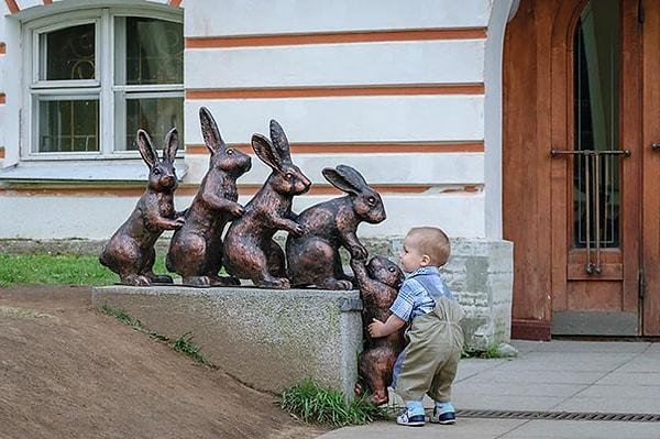 9. Tavşan heykelinin tırmanmasına yardım etmeye çalışan bir çocuk.