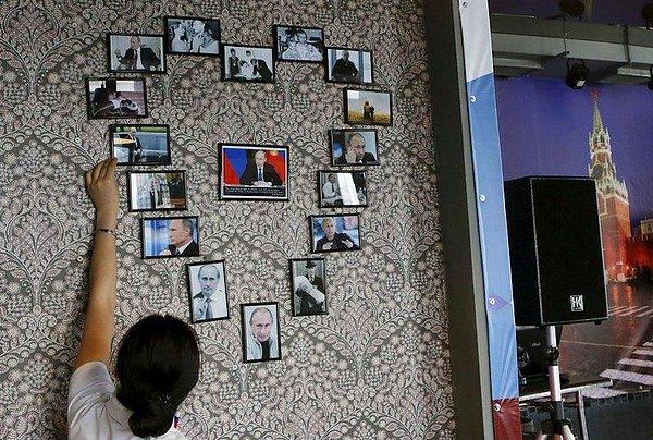 Kafenin çalışanlarından biri, duvara astığı Putin fotoğraflarıyla bir kalp oluşturuyor.
