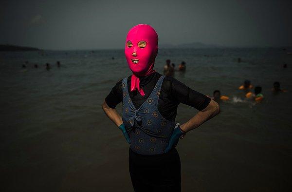 1. Face-kini (Yüzü yanmaktan korumak için denize giderken kullanılan bir tür maske) takmış bir kadın, Qingdao'daki bir plajda poz veriyor. Şantung Eyaleti, Çin. 24 Temmuz 2015.