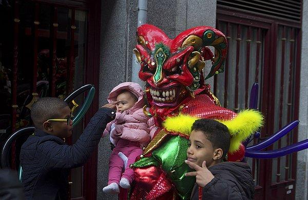 23. Madrid'deki karnaval kutlamaları öncesinde çocuklarla kameralara poz veren maskeli bir katılımcı. İspanya, 6 Şubat 2016.