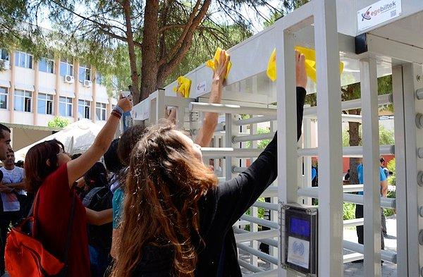 Öğrenci Kolektifleri üyesi öğrenciler getirdikleri deterjanlı suyu turnikelere döküp, cam bezleriye silmeye başladı