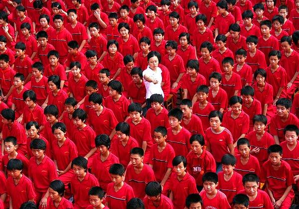 9. Yaklaşan Çin Ulusal Günü için kırmızı giyinen ortaokul öğrencileri ve aralarında yürüten öğretmen.