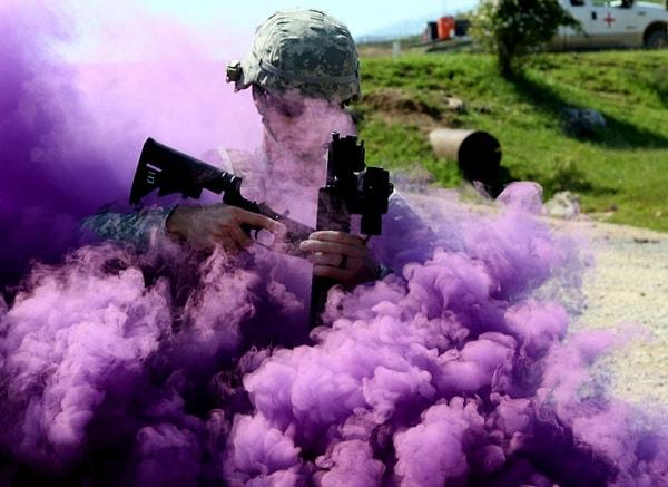 Çokuluslu Muharebe Grubu Doğu'nun En İyi Savaşçısı Yarışması'nda, bir uçuş sıhhiyecisi görüş mesafesini düşüren mor dumanın içinde M4 silahını dolduruyor.