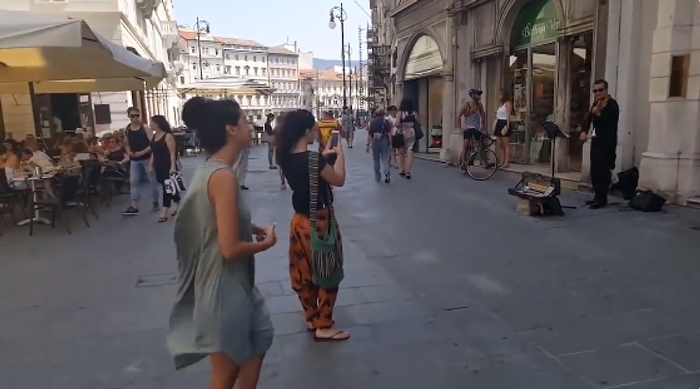 Девушка-туристка танцует на одной из итальянских улочек