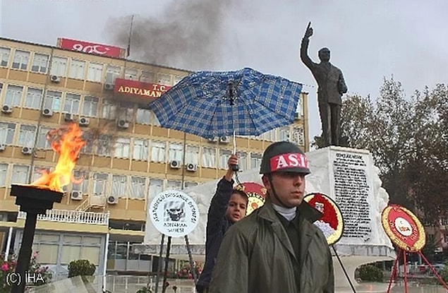 12. This kid holds his umbrella for the soldiers on duty.