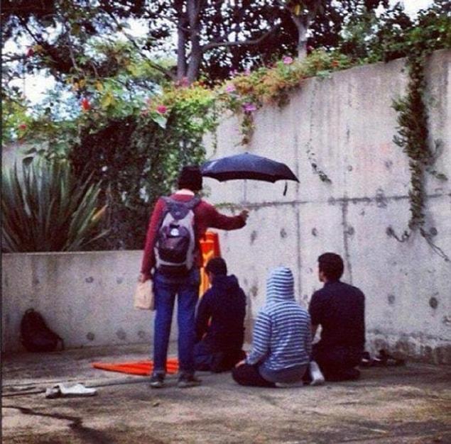 15. A christian student holds his umbrella for the Muslim students during their prayers at California University.