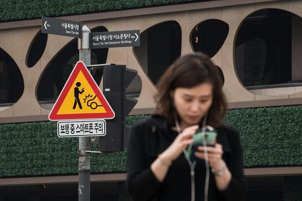 22 Haziran 2016 tarihli bu görselde, Seul'un merkezi bir bölgesindeki ana kavşaklardan birinde, hazırlanmış tabelayla telefon kullanıcıları uyarılıyor