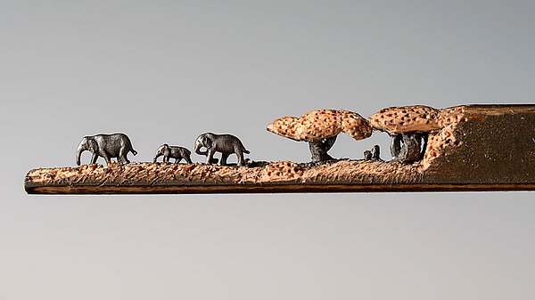 Ağaçların üst kısmını kalemin kendi odunundan, filleri ise kaleme rengini veren kurşunu oyarak yapmış.