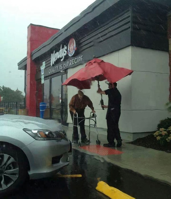 5. Работник кафе снял большой зонт со столика, чтобы помочь мужчине спрятаться от дождя