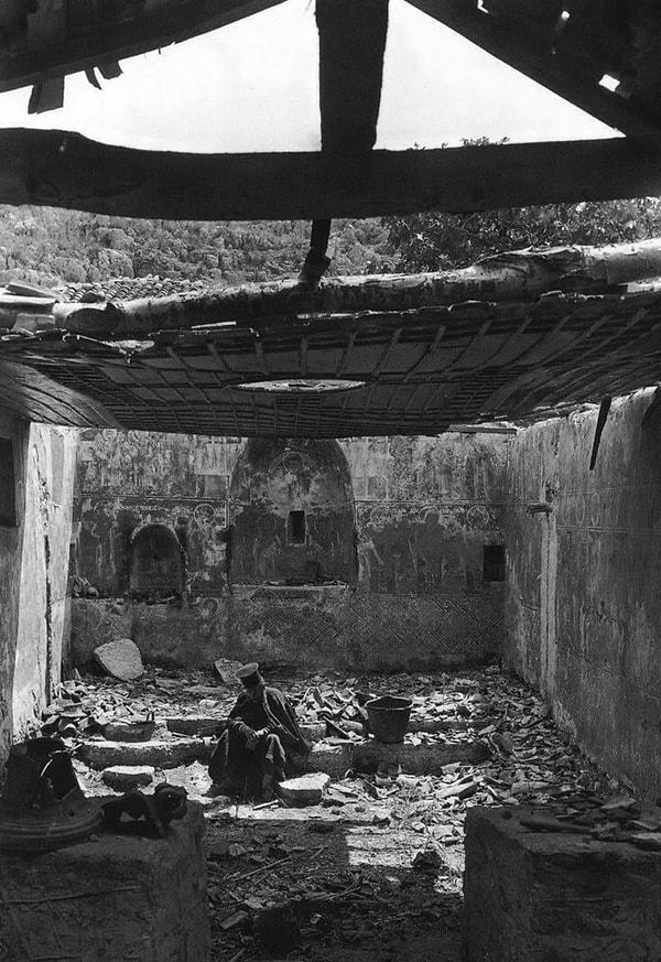 27. Bir Yunan Ortodoks papazı Balkan Savaşı sırasında tahrip edilmiş kilisesinin içinde otururken, Yunanistan, 1913.