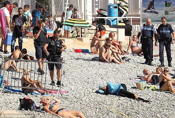Nice kentinde bulunan Promenade des Anglais plajında, o anda uyuyor olduğu görülen bir kadına dört Fransız polis yaklaşıyor.