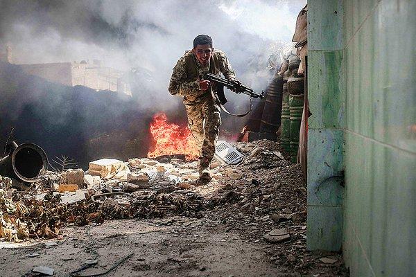 13. Suriye'de asilerin egemen olduğu bir kasabada İslam Ordusu'ndan bir savaşçı, keskin nişancı ateşinden kaçmak için koşuyor.