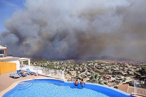 19. İspanya'nın doğusunda Benitachel kasabasının yakınlarında çıkan yangını, iki adam havuzdan izliyor. İspanyol itfaiye görevlileri 1.000 kişinin tahliyesini gerektiren yangını kontrol altına almak için hala uğraşıyorlar.