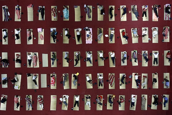 4. Родители спят на циновках, выложенных на полу спортзала внутри университетского городка в Ухане.