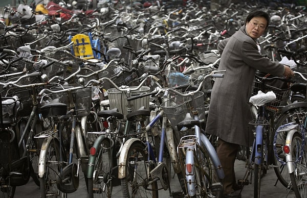 5. Женщина со своим велосипедом на стоянке за пределами станции метро, Пекин.