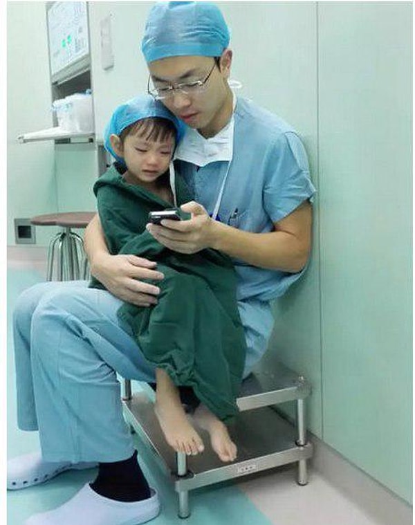 18. Хирург утешает плачущую девочку перед операцией, смотря с ней мультики