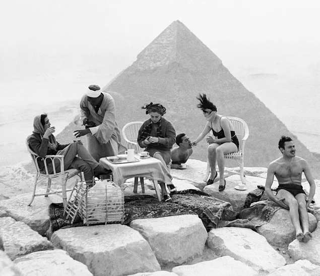 Gize'deki dev piramitlere karşı güneşlenen turistler.