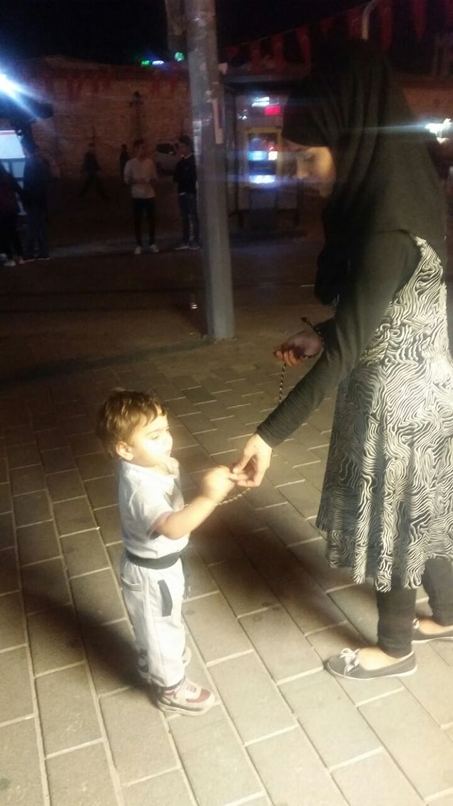 4 -5 yaşlarındaki çocuğunun kaybolmasını önlemek isteyen Arap kadın turist, çocuğunu kolundan kalın bir iple bağlayıp gezdirdi