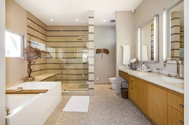 The bathroom is designed with natural earthy colors and wooden textures.