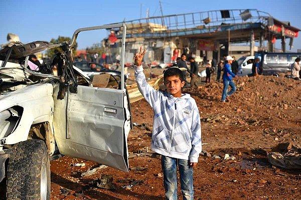 8. Halep kentinde 19 kişiyi öldüren bombalı saldırıdaki aracın yanında bir çocuk zafer işareti yapıyor.