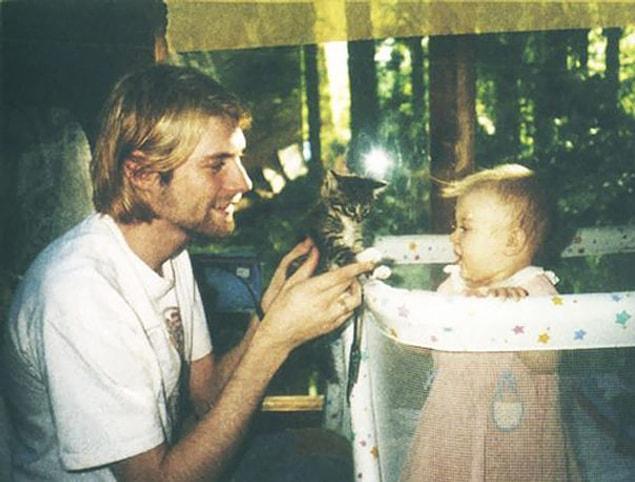 13. 26 year old Kurt Cobain showing a kitten to his daughter Frances, 1993.