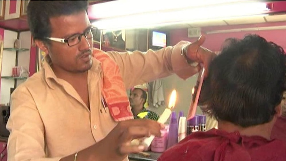 Индийский парикмахер, стрегущий волосы с помощью... свечки