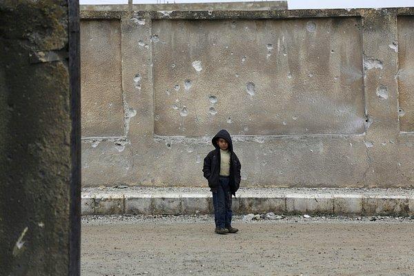 3. Halep'in biraz dışında bulunan İnjara kentinde Rus uçaklarının saldırılarından sonra delik deşik olmuş okul duvarının önünde duran bir çocuk.