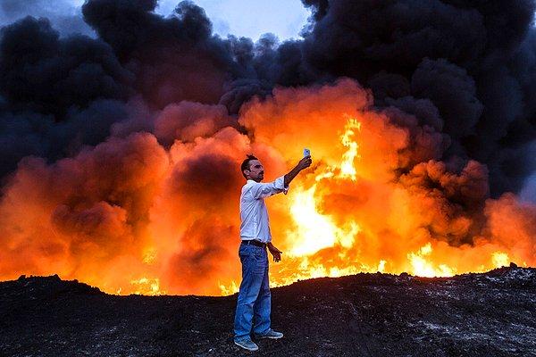 29. Irak güçlerinin IŞİD'e yaptığı operasyon sırasında güney Musul'da ateşe verilen petrol alevleri arasında 'selfie' çeken bir vatandaş.