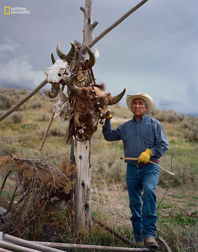 39. Idaho'da, Shoshone-Bannock kabilesi ve bizonlar arasındaki ruhsal bağı temsil etmek isteyen Leo Teton, bizon kafa taslarının asılı olduğu bir direğin yanında poz veriyor.
