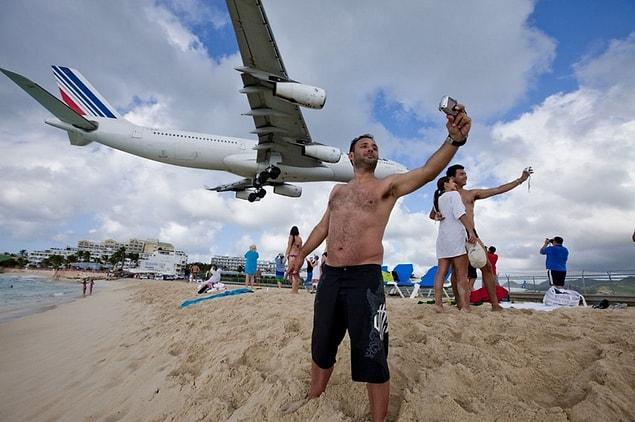 7. People taking selfies with a plane at the Maho beach in Saint Martin.
