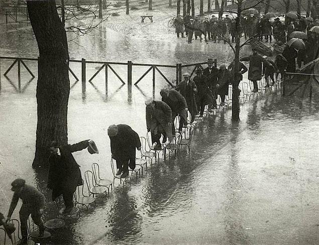 16. Parisians who try to keep their feet dry by standing on chairs, 1924.
