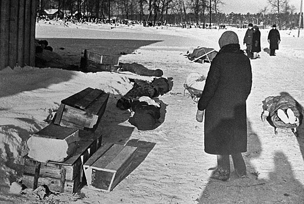 4. Женщина стоит рядом с телами умерших и гробами для их погребения.