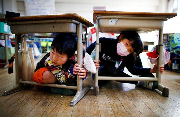 16. Tokyo'da bir deprem tatbikatı sırasında çocuklar sıraların altında. Deprem tatbikatı 11 Mart 2011 depreminin 6. yıl dönümü kapsamında yapıldı.