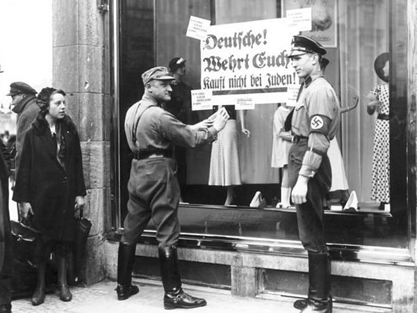 12. Члены нацисткой партии вешают плакат, призывающей ничего не покупать в этой лавке, так как там работают евреи, Берлин. Апрель, 1933