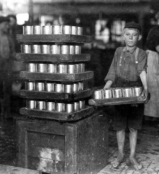 15. A small child carries loads of cans at a food packing plant in Baltimore, Maryland, in 1909.