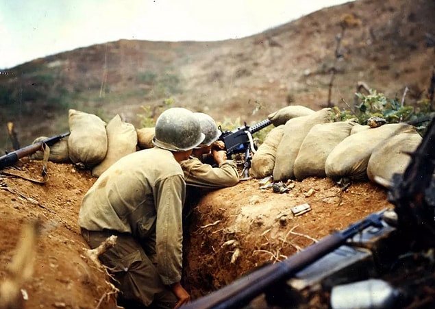 6. Two soldiers train their 30-caliber machine gun on North Korean positions on the western front in 1952.
