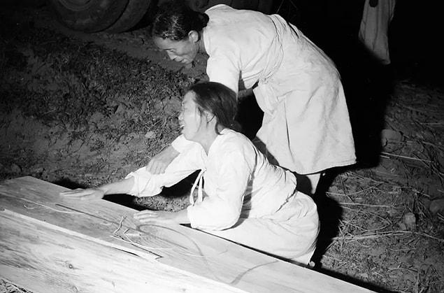 9. A South Korean woman tries to comfort another as she cries over a wooden coffin containing a loved one in 1952.