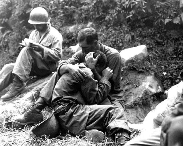 12. An American soldier comforts a comrade in distress following a fierce battle in 1953.