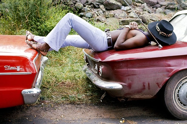 5. A man sleeps stretched across the trunks of two parked cars at the Woodstock Music and Arts Fair in Bethel, New York in 1969.