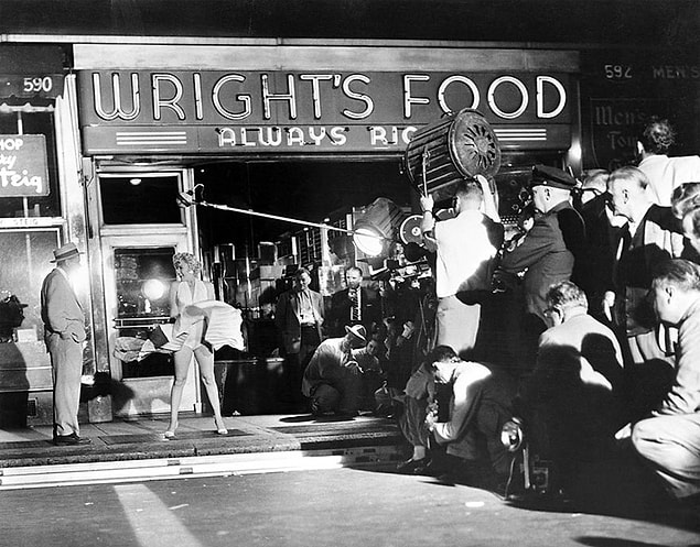 36. Marilyn Monroe playing her role regardless of the gigantic crowd watching her on the legendary film set. | 1954