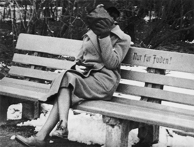 45. A Jewish woman sitting on a bench with the writing, "Only for the Jew," she's hiding her face, Austria. | 1938