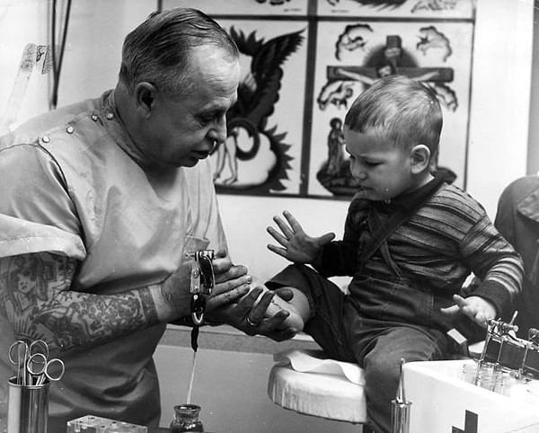 12. Татуировщик из Британской Колумбии, Канада, наносит на ступню мальчика его имя, 1965