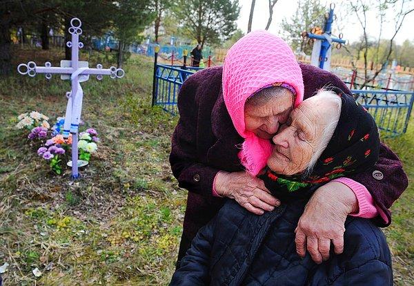 21. Beyaz Rusya'da Çernobil nükleer felaketinden ciddi anlamda etkilenmiş Khoiniki bölgesinde yer alan bir köyün mezarlığında ağlayan kadınlar.