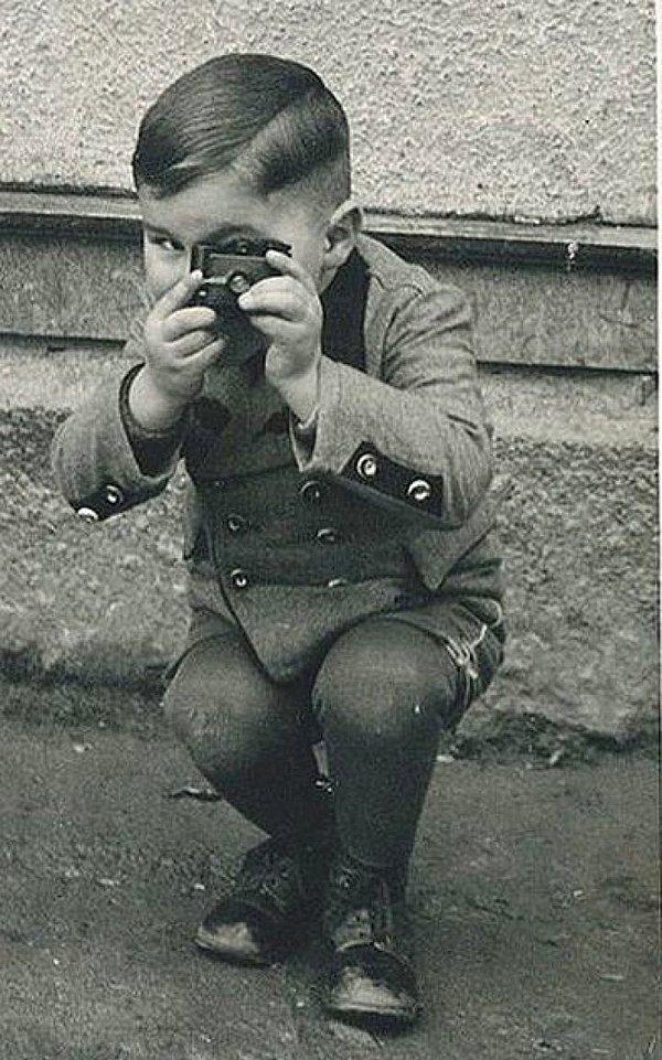 19. Oyuncak kamerayla poz veren küçük bir çocuk, 1910.