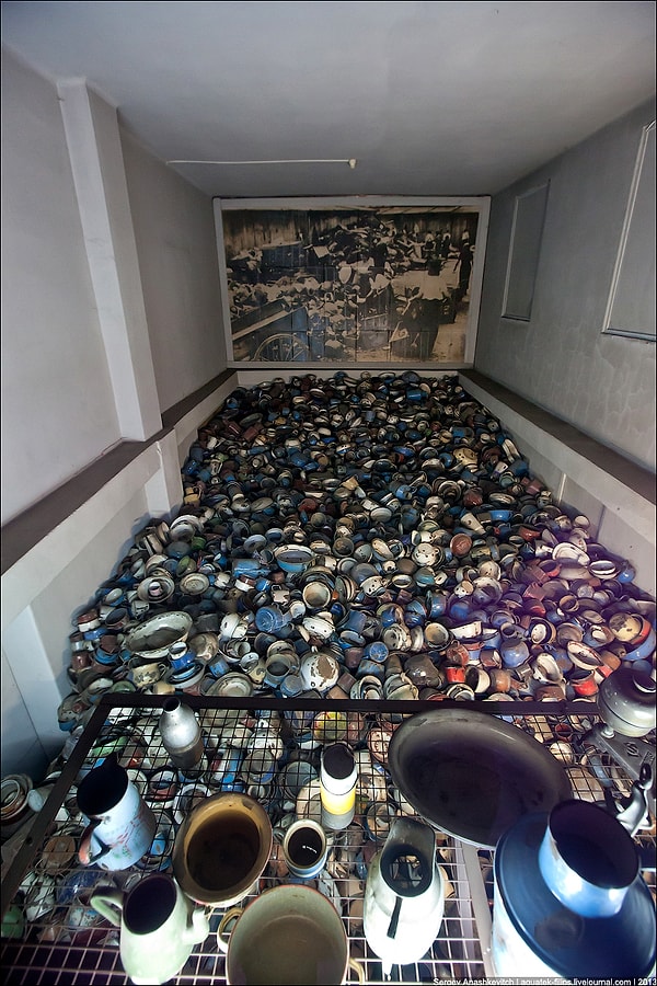 6. Комната, первый этаж которой заполнен металлической посудой из чемоданов узников - миски, тарелки, чайники...