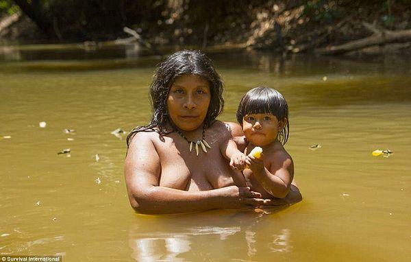 A woman with a child while bathing in a river in the middle of the forest, which is slowly being eradicated by fire and farming.