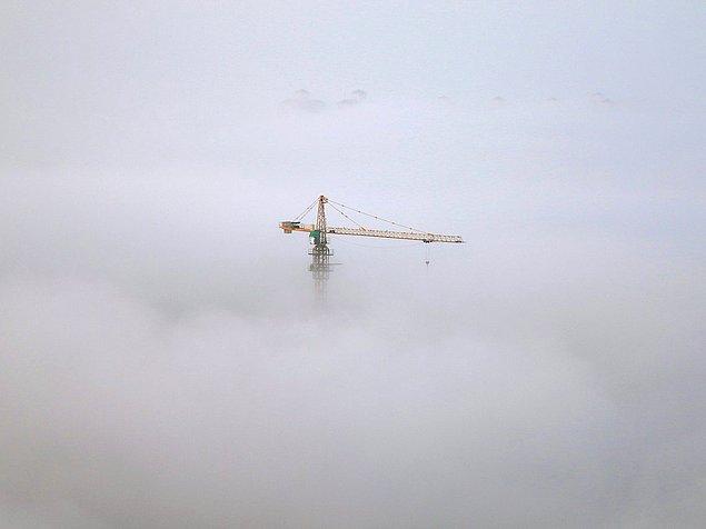 14. Çin'in Shandong Bölgesi'nin liman şehri Yantai'de bulutları delip geçen bir vinç.
